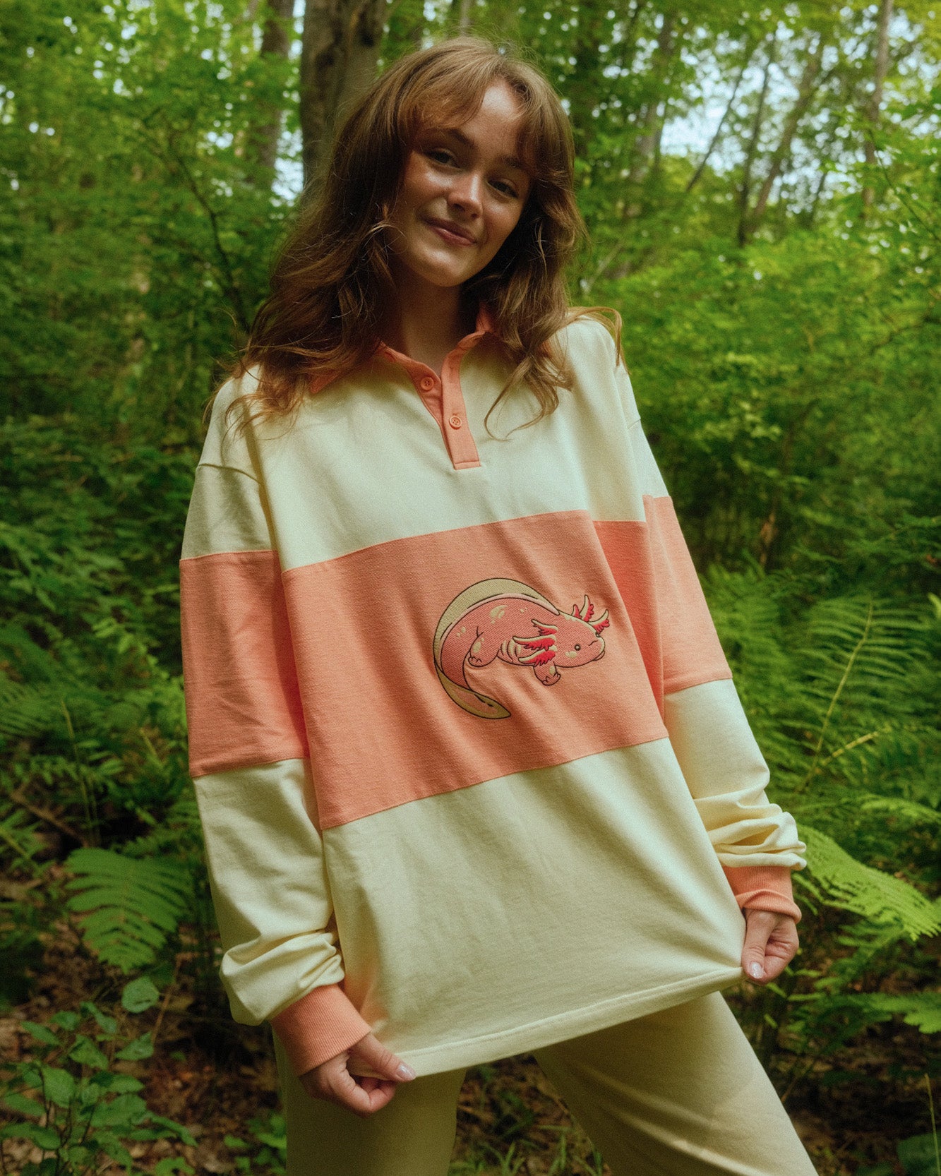 abi toads wearing a pink and white rugby shirt with a axolotl embroidered on the front