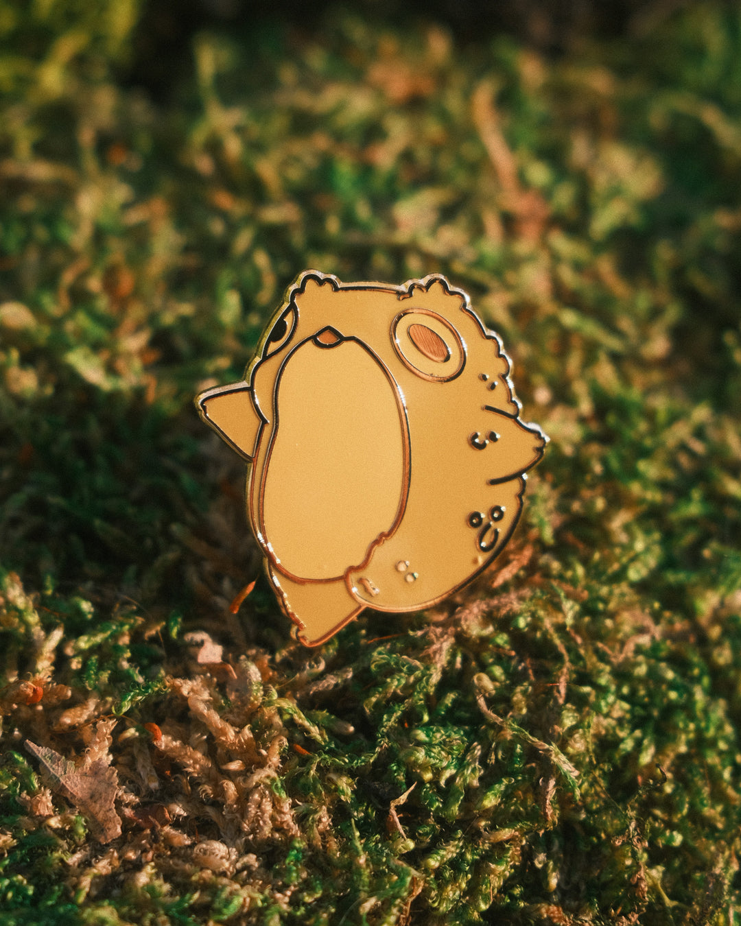 pin of a dancing toad on a mossy background