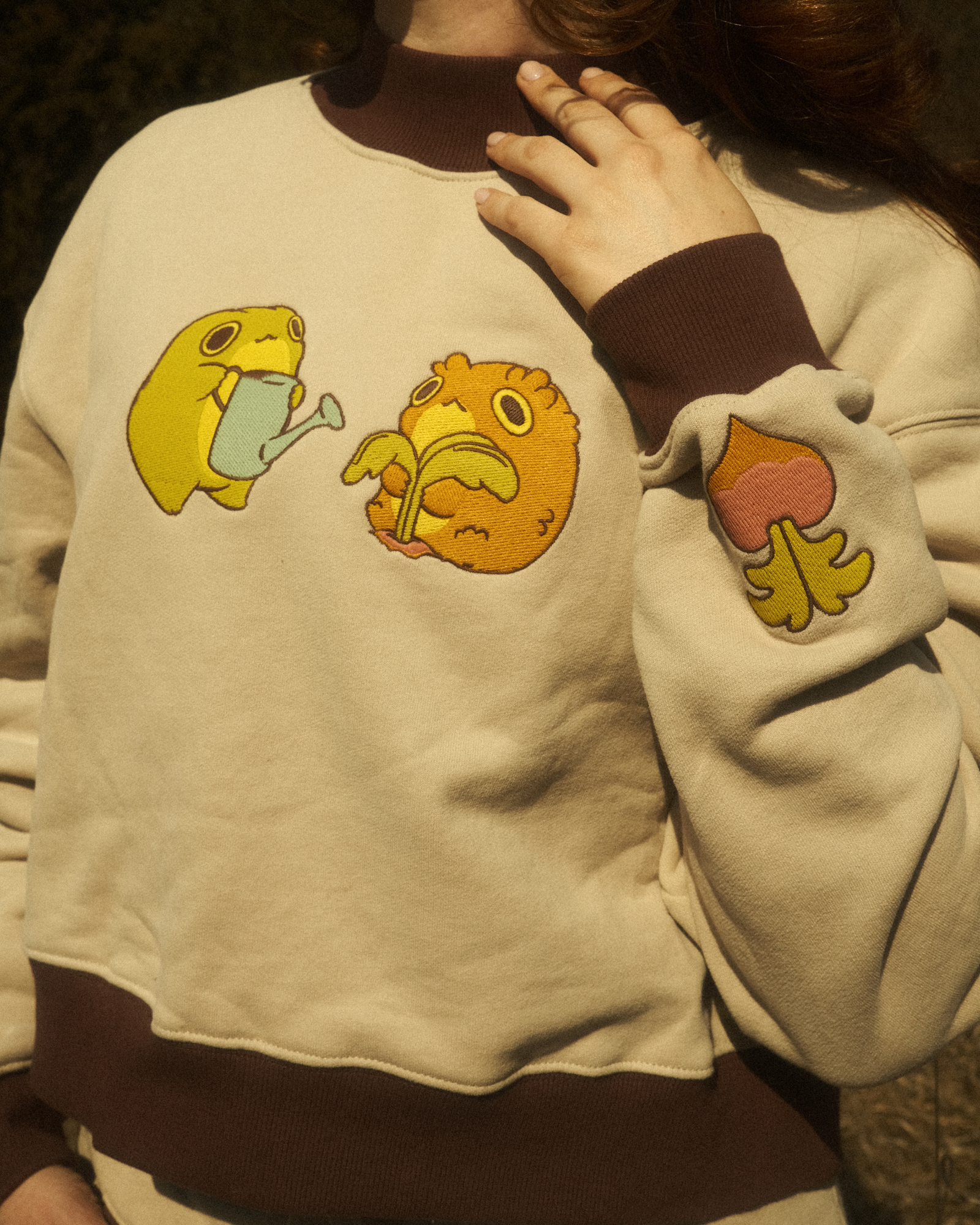 beige sweater with embroidered gardening frogs on the front