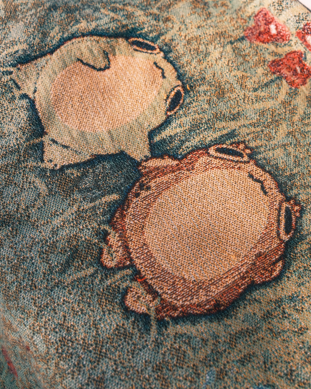 closeup of woven blanket of frogs holding hands in a flowery field