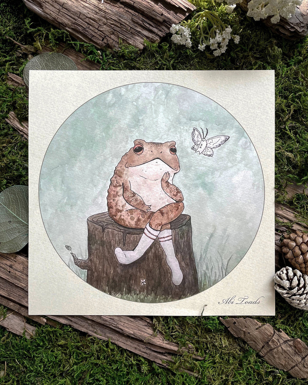 watercolor print with frog sitting on log next to a moth