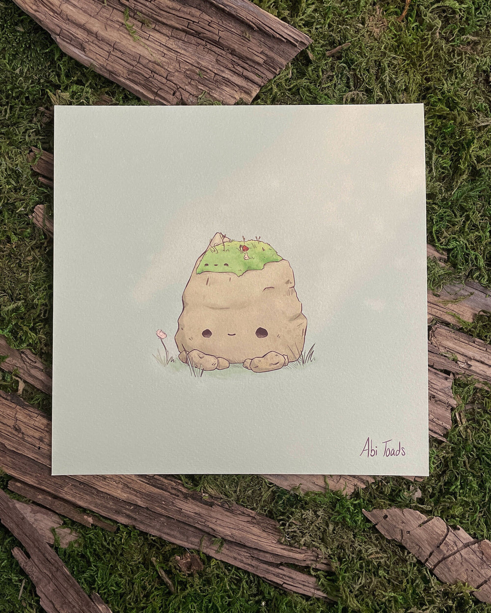 print of a happy rock with a pile of moss on top of his head, hugging it
