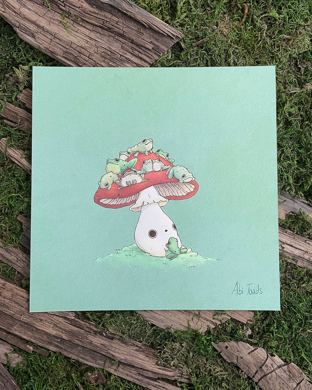 print of red capped mushling with many frogs sitting on top of his head