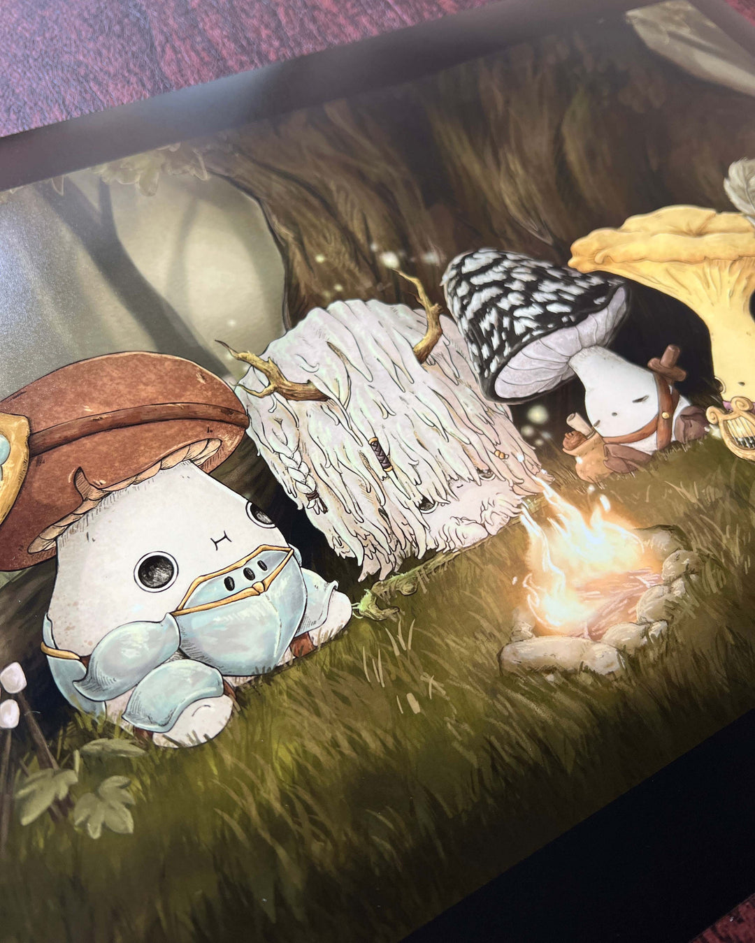 closeup of print of fantasy mushroom characters resting around a campfire