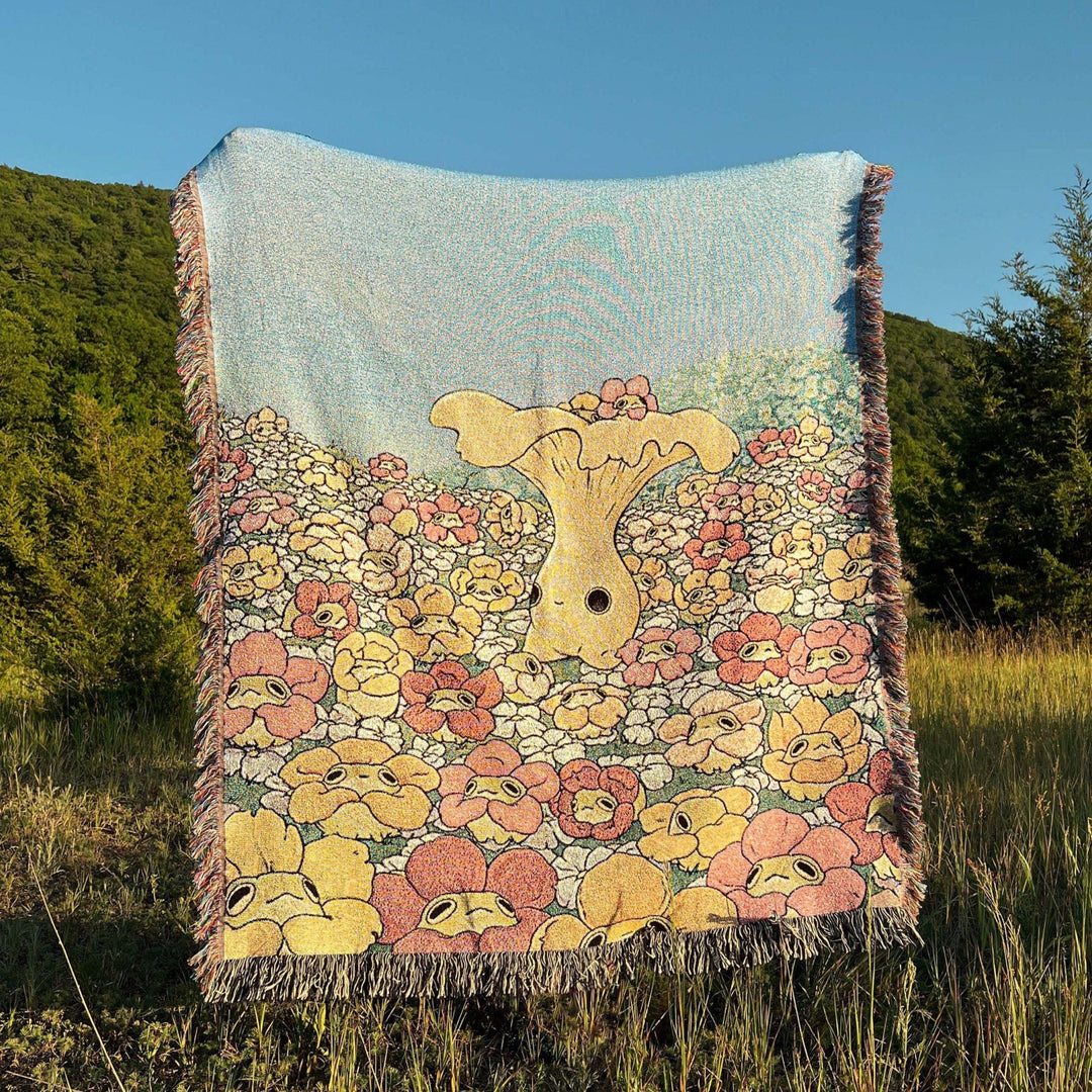 a woven blanket with a chanterelle character surrounded by frogs in flower necklaces