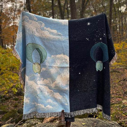 queen sized woven blanket of frogs sliding through a day sky and night sky split between halves of the blanket