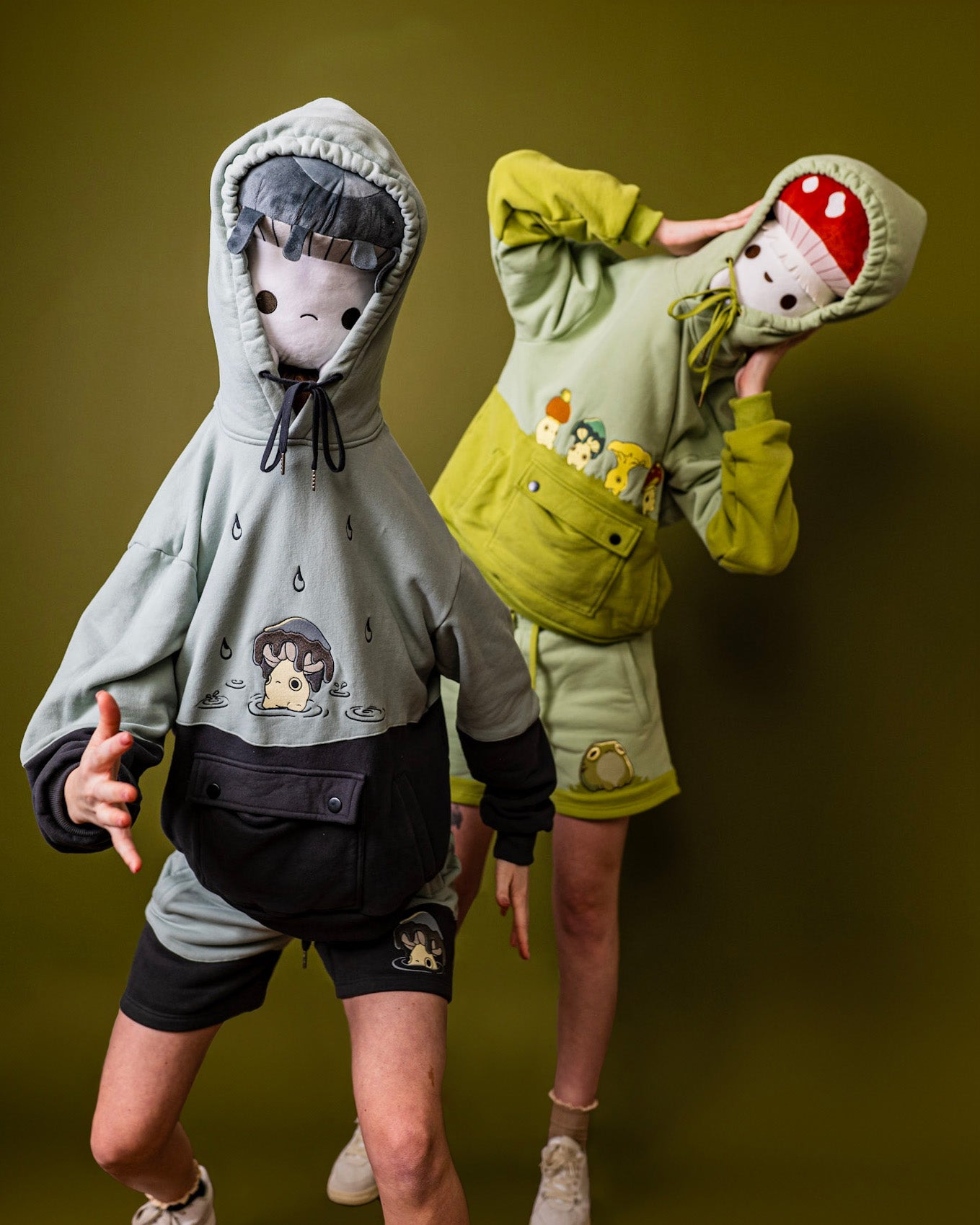 two people in hoodies with mushroom plushies on their heads