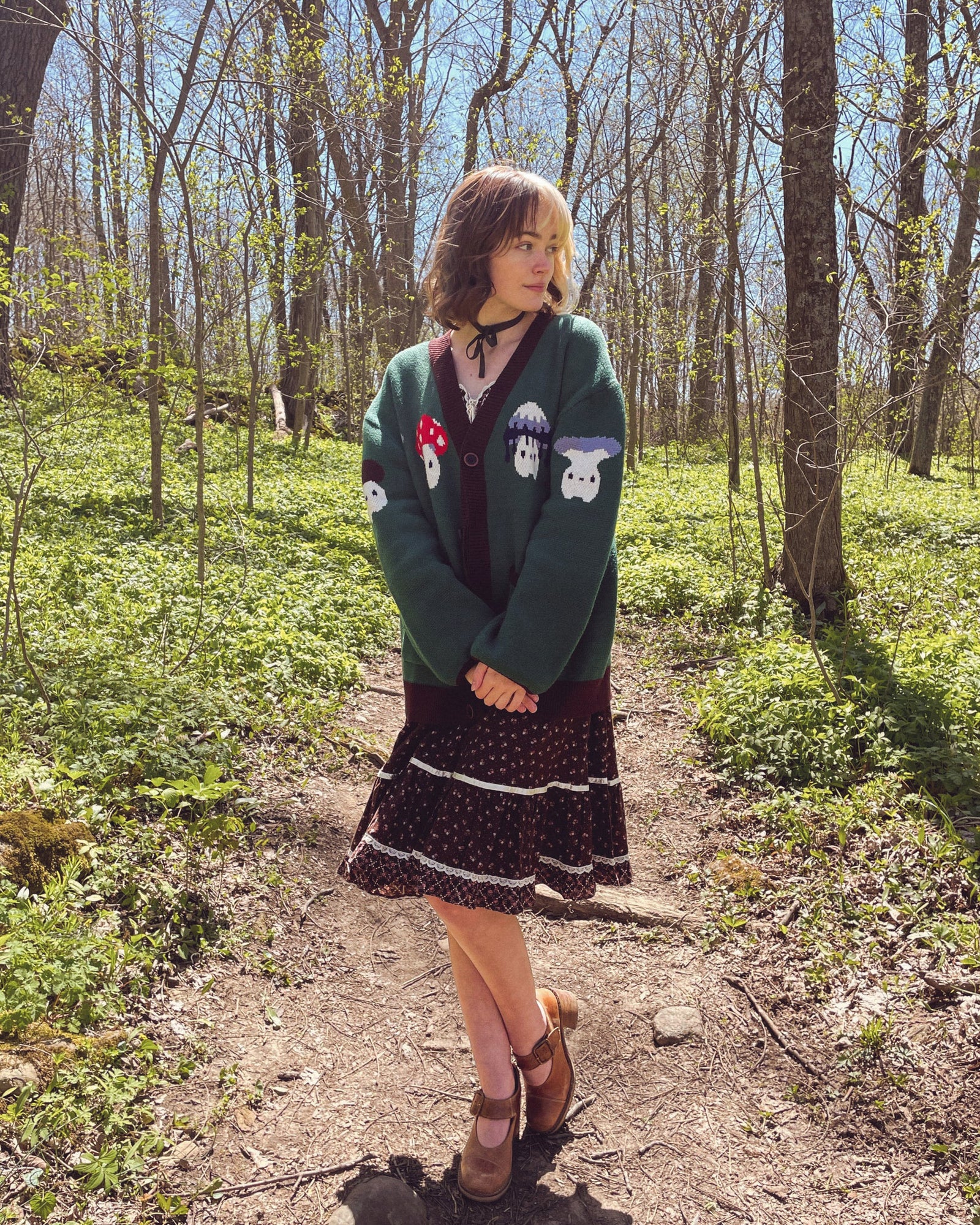 abi toads wearing a green cardigan with various mushlings on it