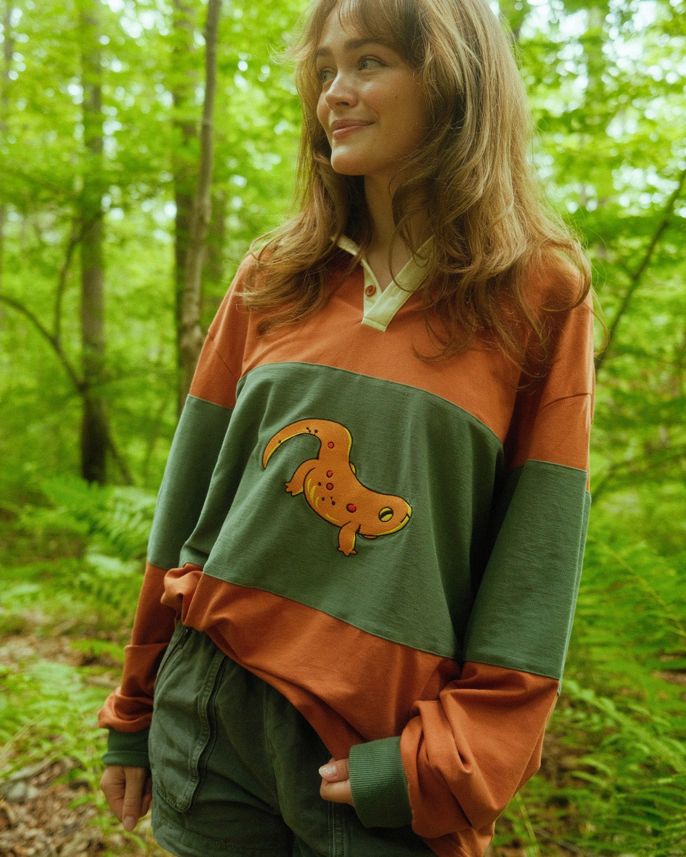 abi toads wearing an orange and green rugby shirt with a newt embroidered on the front