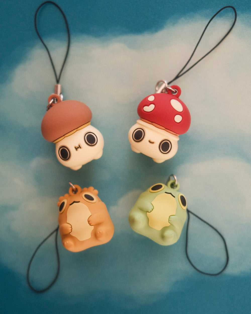 four phone charms, two of mushroom characters, two of frog characters