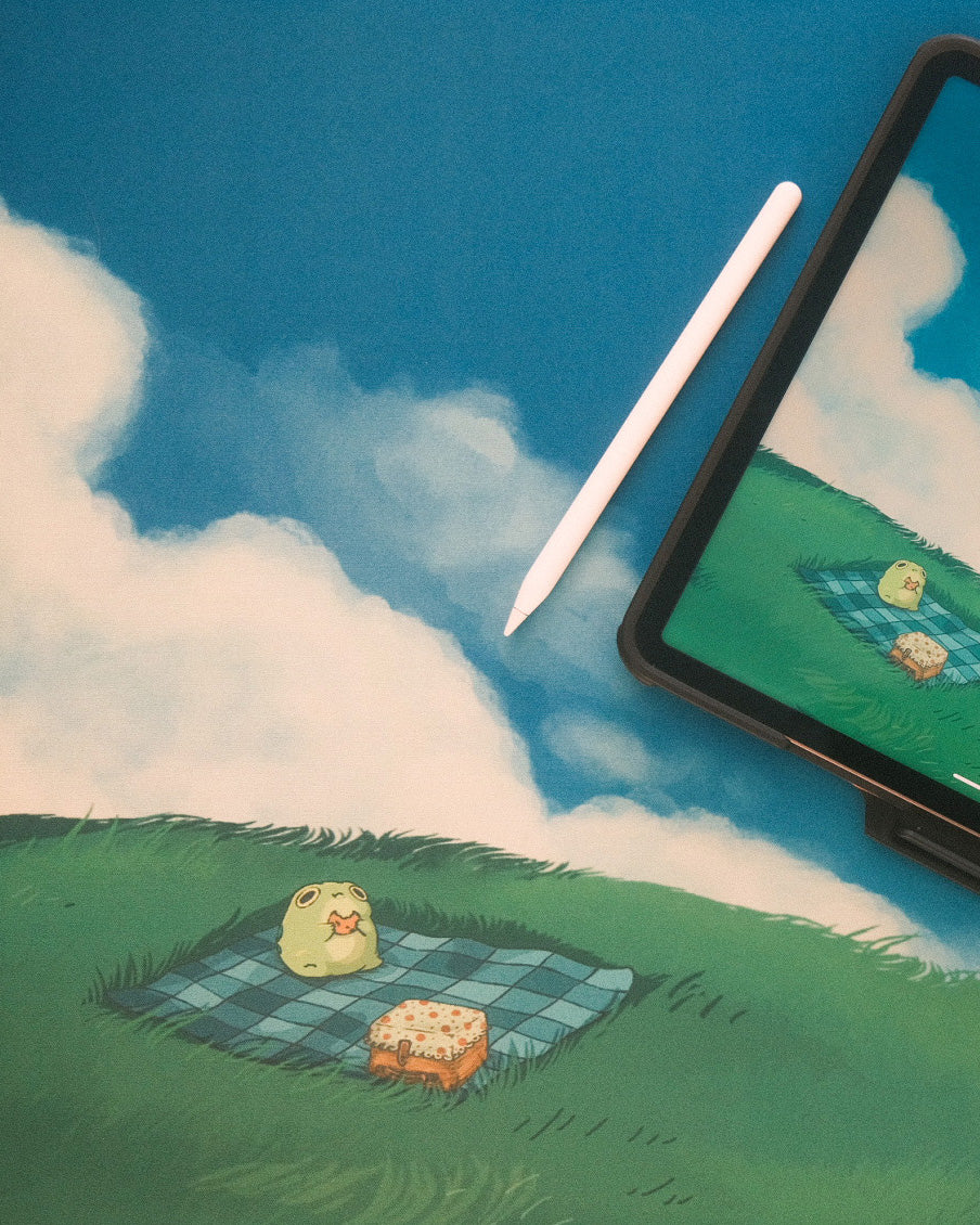 deskmat depicting a frog eating a cookie in a field