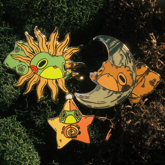 three pins of sun frog, star frog, and moon toad on mossy background