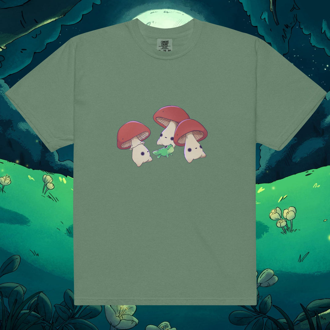 Product mockup of three mushrooms dancing around a frog on a tee shirt