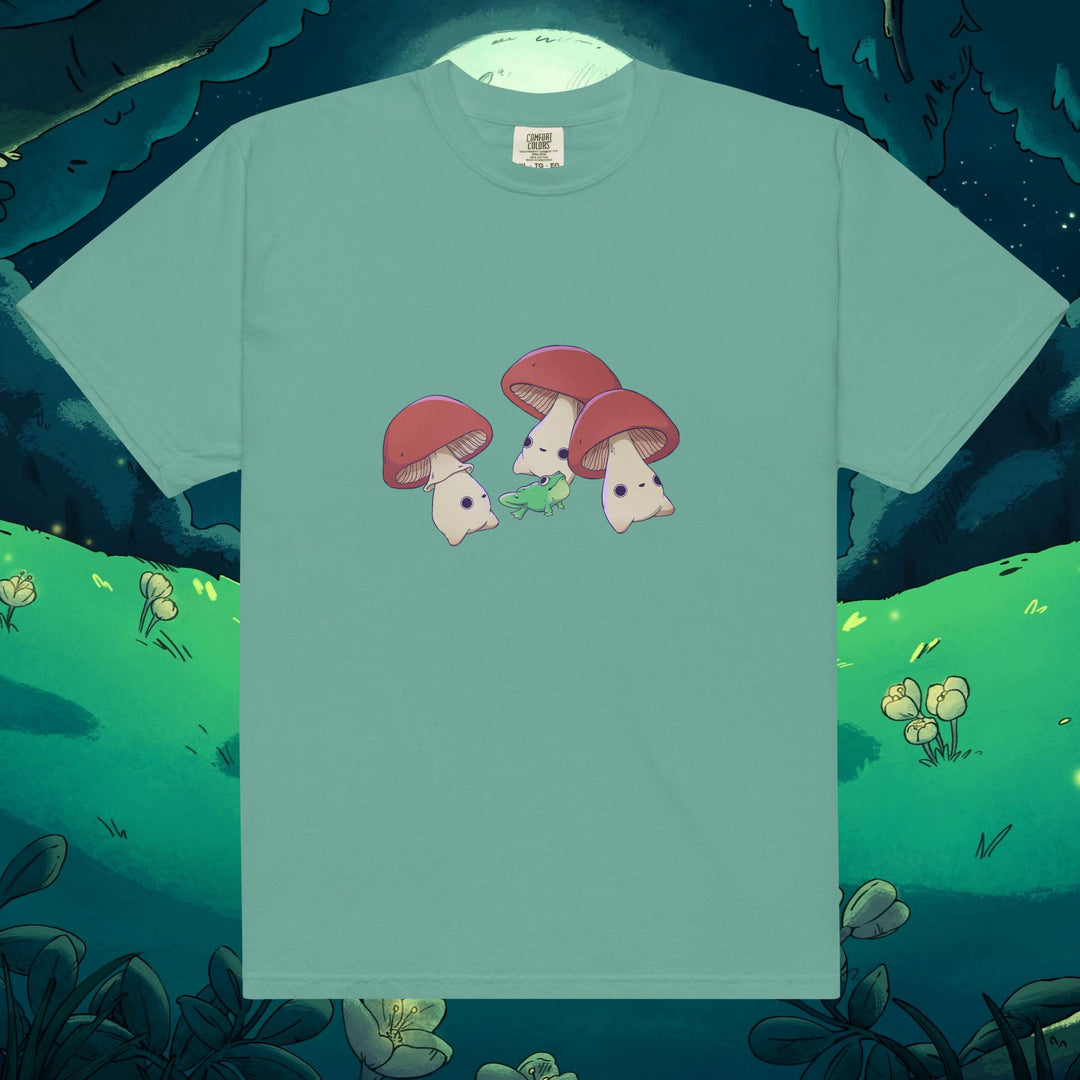 Product mockup of three mushrooms dancing around a frog on a tee shirt